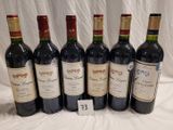 six bottles of red wine are lined up on a table