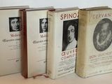 Trois livres sont alignés sur une table devant un mur blanc.