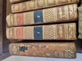 several old books are stacked on top of each other on a shelf