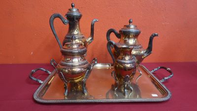 two silver teapots sitting on a tray on a table