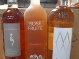 three bottles of rose wine sit on a cardboard box in a warehouse