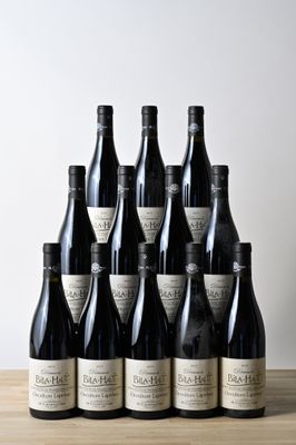 six bouteilles de vin sont posées sur une table en bois devant un mur blanc