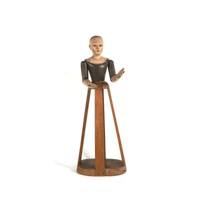une petite statue représentant une femme debout sur un socle en bois