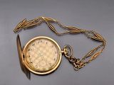 a gold pocket watch on a chain with a chain around it