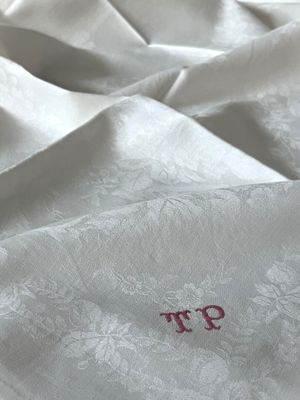 un gros plan d'un lit avec une couette blanche et un t-shirt rouge posé dessus