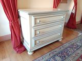 une commode blanche dans une pièce aux rideaux rouges