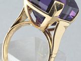 a close up of a ring with a purple stone in it
