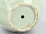 a green vase with a hole in the middle of it