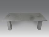 La table est en béton et possède un piètement en métal.