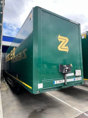 two green semi trucks parked in a parking lot