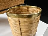a wicker basket with a gold handle on a white table