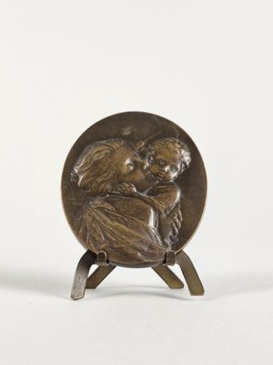une image représentant une plaque en bronze sur laquelle figure une femme tenant un bébé dans ses bras