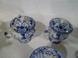 trois tasses à thé bleues et blanches avec leurs soucoupes, posées sur une table