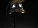un casque en bronze posé sur un socle, coiffé d'un bonnet rouge