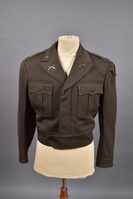 une veste d'uniforme militaire posée sur un mannequin, sur fond gris