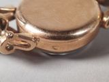 a close up of a gold watch with a chain around it