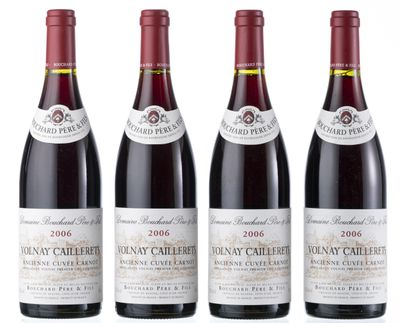 quatre bouteilles de vin sont alignées sur une surface blanche