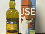 a bottle of chartreuse next to a box on a table