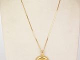 a gold necklace with a coin on a mannequin neck