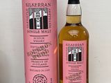 une photo d'une bouteille de whisky posée à côté d'une boîte rose