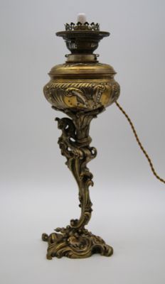 une lampe ancienne en laiton à laquelle est attachée une chaîne au niveau de son socle