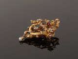 an image of a gold broochle with pearls on a black surface