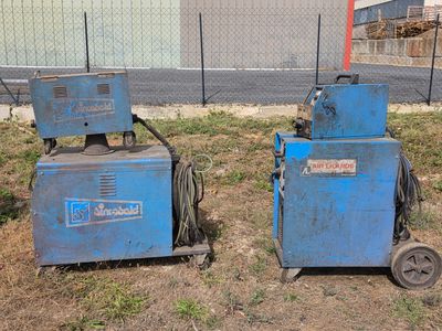 two blue machines that are sitting in the grass