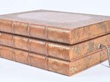 three old books stacked on top of each other on a white surface