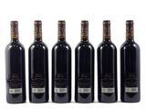 six bottles of wine are lined up on a white surface