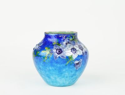 a blue vase with purple flowers on it on a white surface