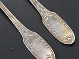two silver spoons sitting on top of a table next to each other