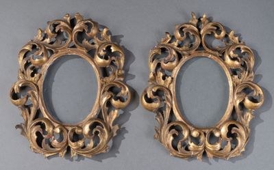 pair of ornate gold oval mirrors on a gray surface