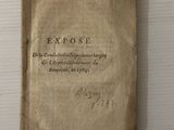 un vieux livre posé sur une table blanche, à côté d'une étiquette