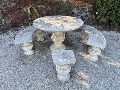 une table en pierre et deux bancs en pierre dans un jardin