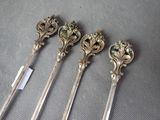 four silver spoons with ornate designs on them sitting on a table