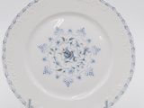 a white plate with blue flowers on it on a stand