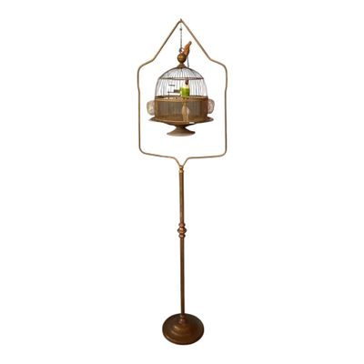 a bird in a cage on a stand with a white background