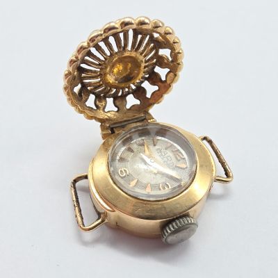une image d'une montre de poche en or sur une surface blanche