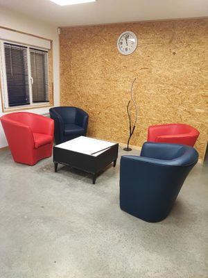 trois chaises et une table dans une pièce où est accrochée une horloge au mur