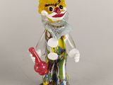 un petit clown en peluche avec un chapeau rouge et un haut-de-forme noir