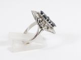 an image of a diamond and sapphire ring on a clear acrylic stand