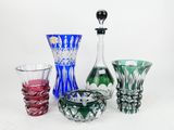 four different colored glass vases sitting on a white surface