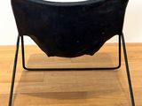 black leather chair with metal frame on wooden floor with white wall