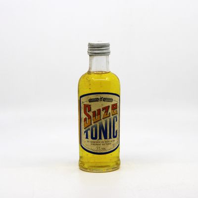 un gros plan d'une bouteille de tonic posée sur une surface blanche