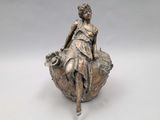 bronze statue of a woman sitting on a leaf with a basket of flowers