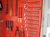 many tools hanging on a red wall in a garage