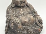 une vieille statue représentant un Bouddha souriant, assis sur une surface blanche