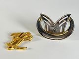 a silver and gold brooch with a knot on it