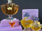 several different perfume bottles are sitting on purple boxes on a table