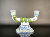 un vase bleu et blanc muni d'une anse verte, posé sur une table noire